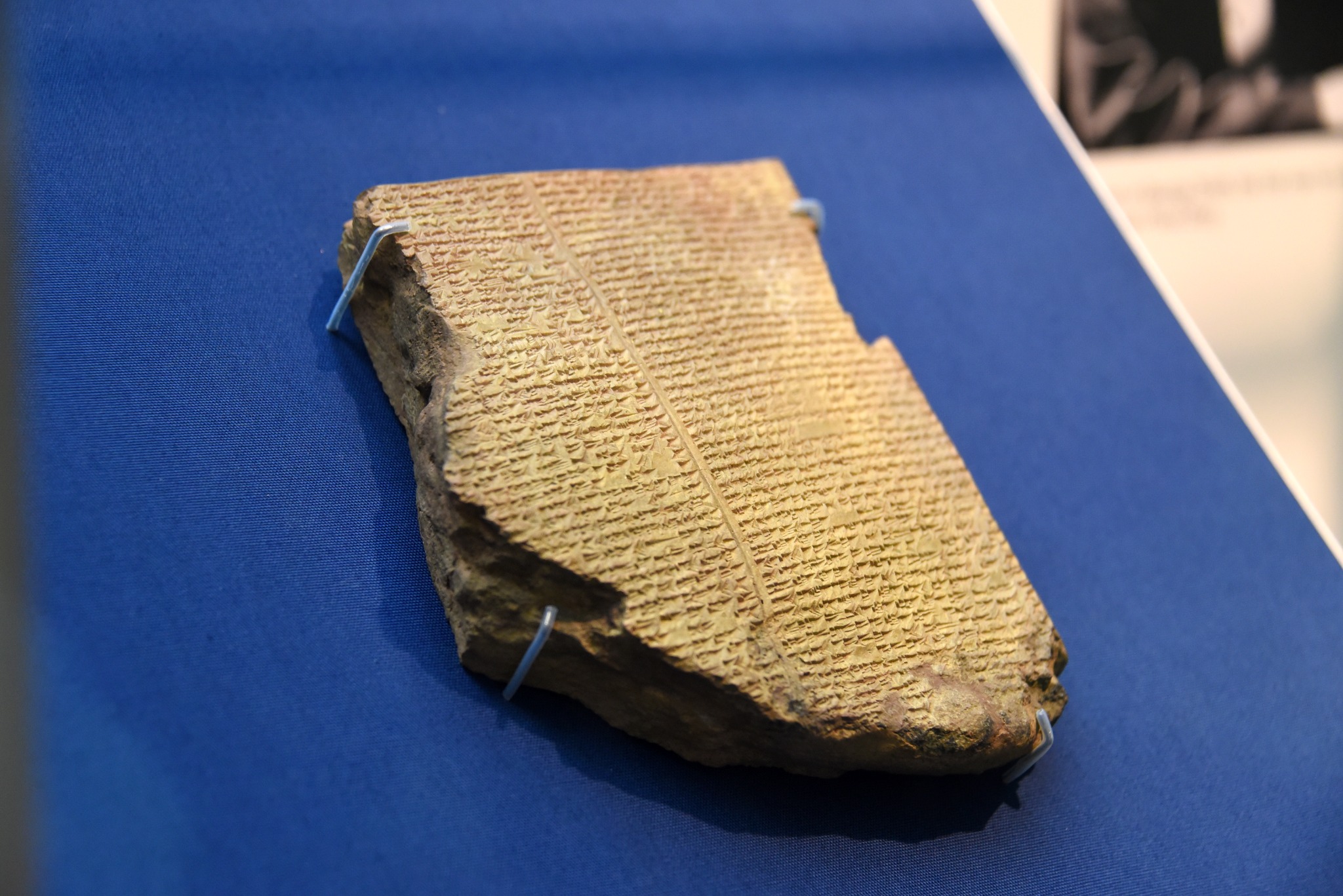 Cuneiform Flood Tablet from Tablet XI of the Epic of Gilgamesh displayed on a blue museum mount.